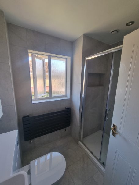 modern walkin shower in peterborough •Modern grey towel rail •Manhattan grey bathroom wall tiles •Toilet and basin combination unit •Contemporary bathroom design